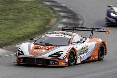 Bulutlu ve yağmurlu bir günde yarış pistinde süper hızlı bir araba, McLaren 720 'ler