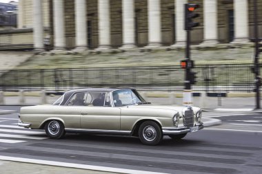 Mercedes Benz W111 'in uzun pozlu bir çekimi klasik lüks araba Paris, Fransa' da bir trafik ışığına izinsiz giriyor.