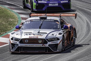 Yarış pistinde hızlı bir yarış arabası, gümüş ve turuncu renkte. Marc II V8