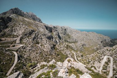 Açık gökyüzünün altında yolları olan güzel bir dağ manzarası.