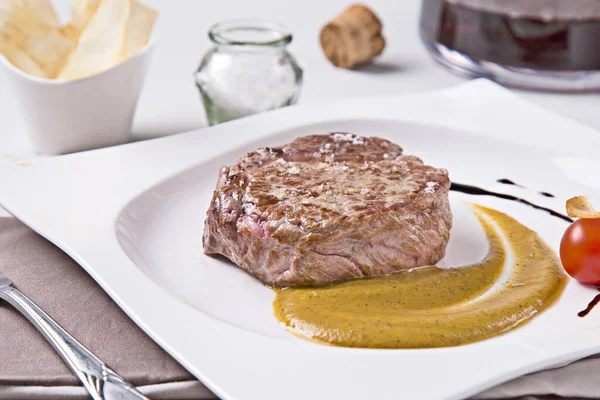 白いプレートの上にソースとおいしいジューシーなステーキのクローズアップショット — ストック写真