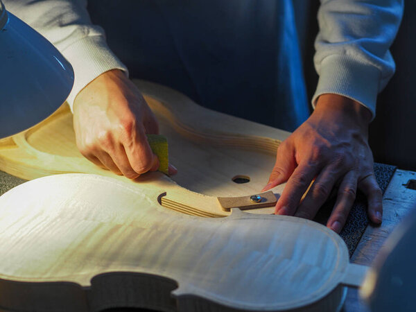 A closeup shot of luthier hands working on a new violin in his workshop