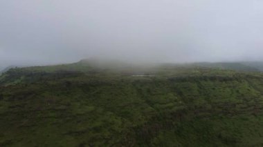 Arkasında gri bulutlar olan bir dağ manzarası.