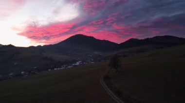 Renkli günbatımında dağlarla ve çayırlarla manzaralı bir manzara.