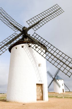 Arka planda bir tane daha olan beyaz bir İspanyol yel değirmeninin yakın çekimi.