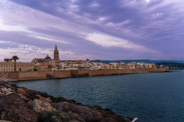 Sardinya 'daki Alghero kıyı kasabası. Denizde sakin mavi bir su var.