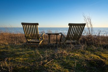 İsveç plajında yakın plan ahşap sandalyeler.