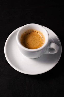 Siyah arka planda beyaz bardakta taze bir kahve.