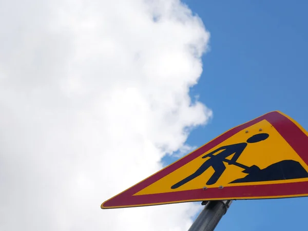 Construction sign against cloudy sky