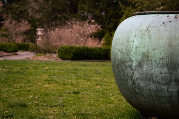 庭の芝生の地面に風化した古い灰色の大きな金属製のピッチャー — ストック写真