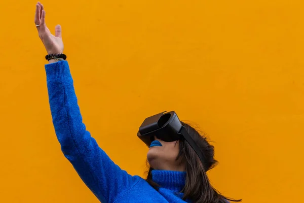 A woman in blue clothes wearing vr glasses and touching something invisible in virtual reality