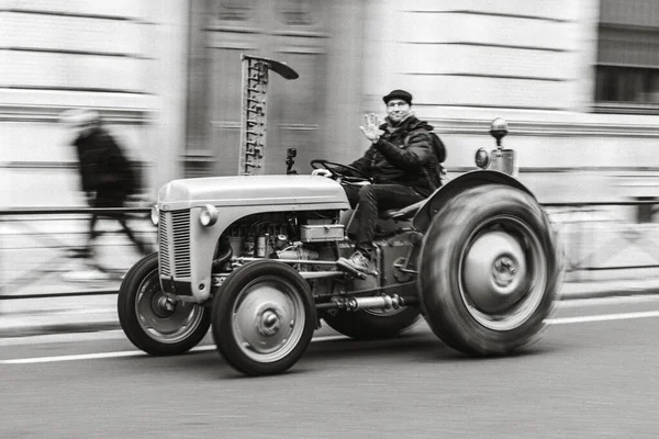 市内の古典的なトラクターを運転する男の灰色のスケール — ストック写真
