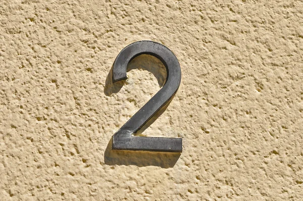 A closeup shot of metal number two on a bright wall outdoors