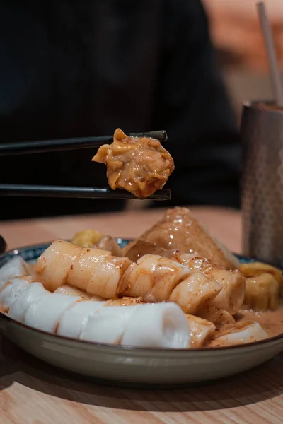 マカオの広東料理店で蒸し団子と麺ロールを握る箸のクローズアップ — ストック写真