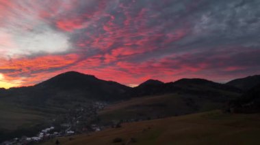 Renkli günbatımında dağlarla ve çayırlarla manzaralı bir manzara.