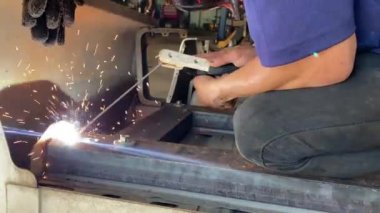 Otomotiv fabrikasında kaynak yapan adamın yakın çekim görüntüleri..