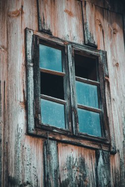 Terk edilmiş ahşap bir kulübenin eski penceresinin dikey görüntüsü.