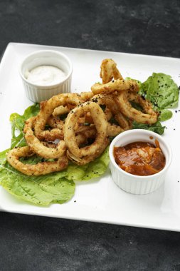 Farklı soslu leziz kızarmış soğan halkalarından dikey bir shot.