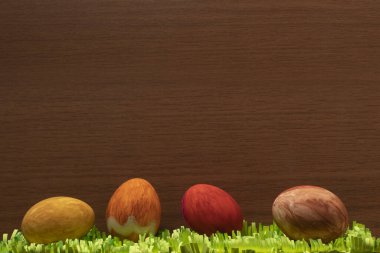 Kahverengi ahşap bir yüzey üzerinde kağıt çimenler olan Paskalya yumurtalarının yakın çekimi.