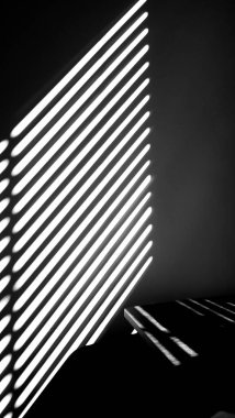 Dikey gri ölçekli bir güneş ışığı görüntüsü pencereden odaya ışınlanıyor.