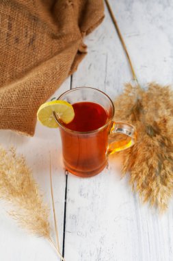 Beyaz, ahşap bir yüzey üzerinde sıcak bir çay bardağının yakın çekimi.