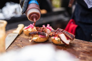 Bir şefin elleri ahşap bir masada iştah açıcı bir burger hazırlıyor.
