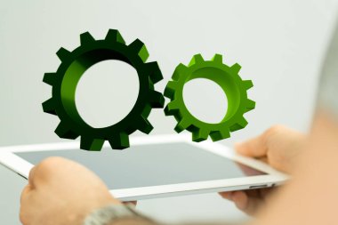 Birinin elinde beyaz bir tablet tutan iki yeşil dişli simgesi. Teknoloji konketi