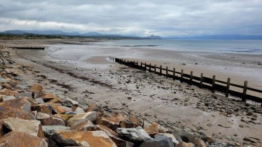 Hafan Y Mor Plajı 'nda çitli kayalar ve bulutlu gökyüzünün altında deniz.