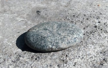 Güneş ışığında taş yüzeyde yatan düz bir taşın yakın çekim görüntüsü..