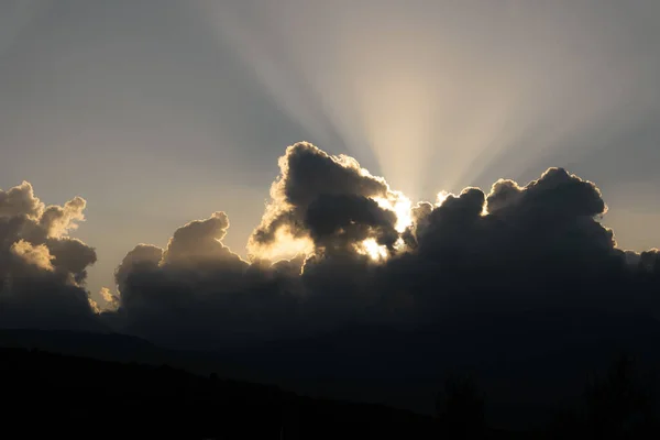 太陽は山の後ろの雲や夕日を通して輝き — ストック写真