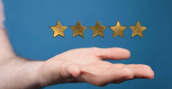 A closeup shot of 3d golden five rating stars on a hand with a blue background, rating concept