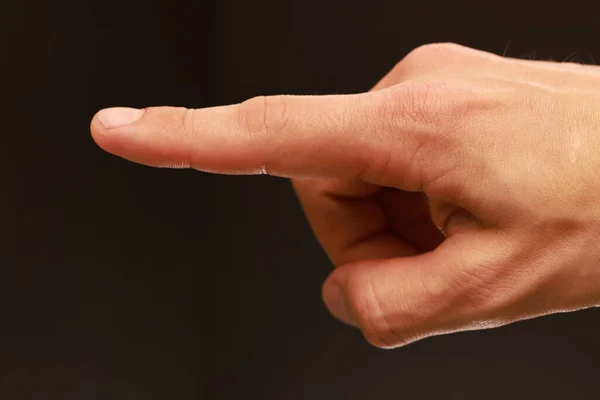 A closeup of an index finger pointing out isolated on a brown blurry background
