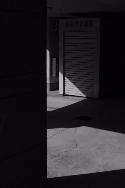 光線が来る暗い廊下の垂直グレースケールショット — ストック写真