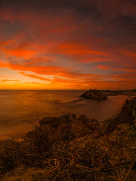 美丽的草地岩石长期暴露在雄伟的海水与令人敬畏的橙色日落的天空 — 图库照片
