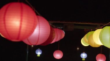 Renkli ışıklı kağıt fenerler rüzgarda sallanan ipten sarkıyor