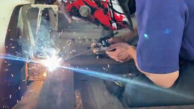 Otomotiv fabrikasında kaynak yapan adamın yakın çekim görüntüleri..