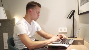 Aktif çalışırken ya da evde ders çalışırken daktilo eden genç bir erkek.