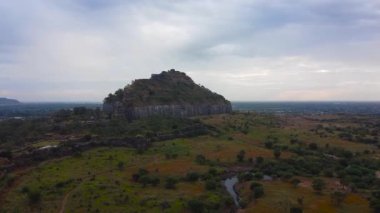 Devgiri Kalesi 'nin bulutlu gökyüzünün altında büyük yeşil bir manzarası.