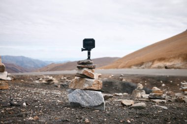 Kayaların üzerinde siyah bir kamera, gün ışığında manzarayı çekiyor.