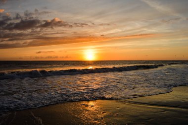 Parlak bir günbatımı, Almanya 'nın Borkum sahilindeki okyanusa yansıdı.