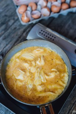 Kızartma tavasında çırpılmış yumurta, gaz sobasında yumurta dolu karton yumurta.