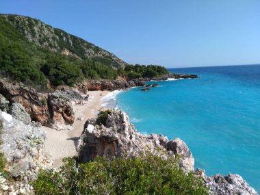 Kayalıklarla güneşli bir sahilin güzel bir görüntüsü.