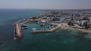 Turkuaz bir denize karşı oteller ve binalarla kaplı kumlu bir sahilin kuş bakışı görüntüsü.