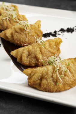 Dikey olarak beyaz tabakta kızarmış hamur köftesi.