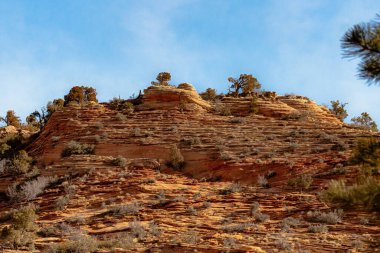 Bulutlu mavi gökyüzünün altındaki kumtaşı uçurumunun alçak açılı görüntüsü.