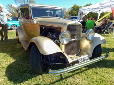 Chascomus, Arjantin - 9 Nisan 2022: Eski bej renkli Ford Model B 18 V8 Tudor sedan 1932. Doğa yeşili çimenler ve ağaçlar. Klasik araba şovu. Kopyalama alanı