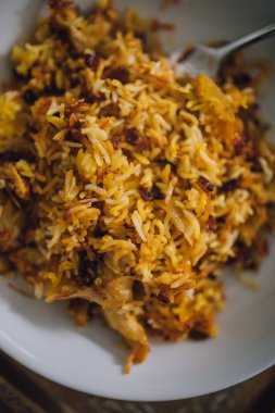 Beyaz tabakta servis edilen tek tavuklu Saffron Barberry Rice (Zereshk Polo ba Irani)