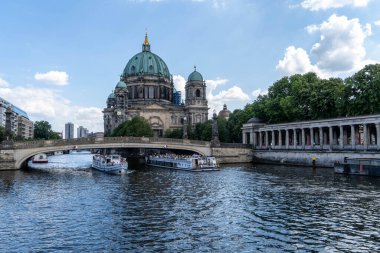 Berlin Katedrali 'nin önünde turist dolu teknelerle dolu Spree nehrinin güzel bir manzarası.
