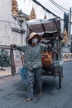 Kamboçya 'da Phnom Penh caddesinde maske takan Asyalı bir erkek satıcı.