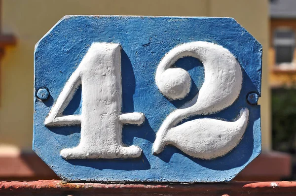 A close-up shot of the number 42 on a metallic textured signboard.